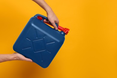 Photo of Man holding blue canister on orange background, closeup. Space for text
