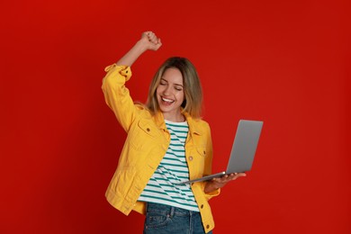 Photo of Young woman with modern laptop on red background