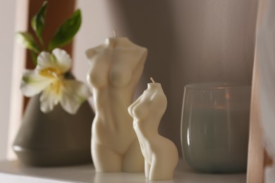 Photo of Beautiful body shaped candles and flower on shelf