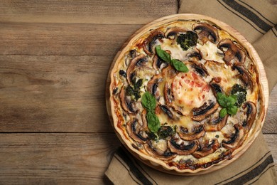 Delicious quiche with mushrooms and basil on wooden table, top view. Space for text