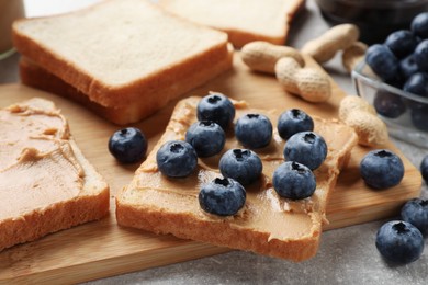Photo of Tasty peanut butter sandwiches with fresh blueberries on table, closeup
