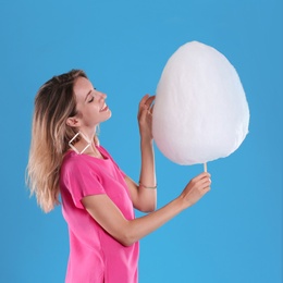 Photo of Happy young woman with cotton candy on blue background