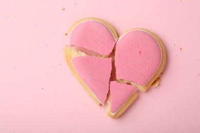Photo of Broken heart shaped cookie on pink background, top view. Relationship problems concept