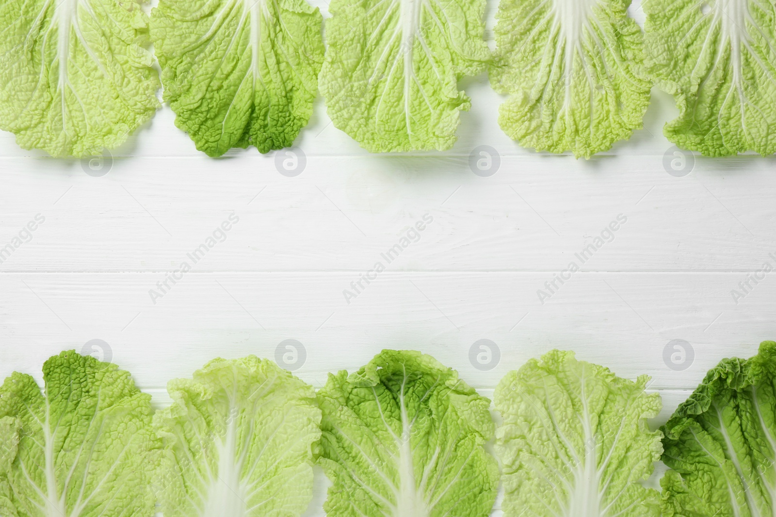 Photo of Fresh ripe leaves of Chinese cabbage on white wooden table, flat lay. Space for text