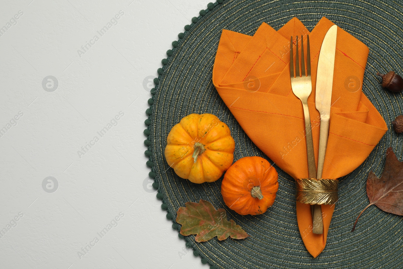 Photo of Cutlery, napkin and autumn decoration on white background, flat lay with space for text. Table setting