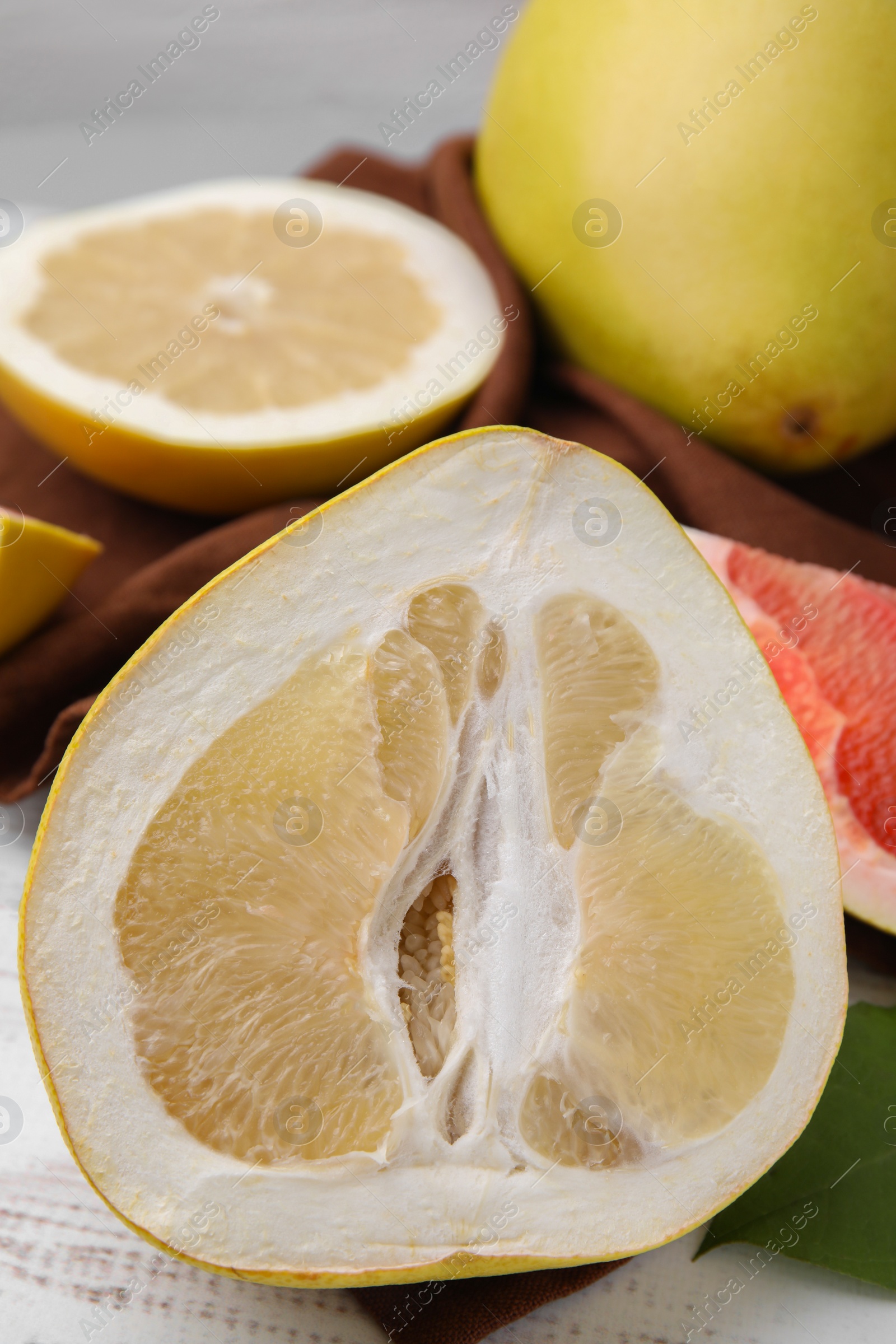 Photo of Different sorts of tasty pomelo fruits on white wooden table, closeup