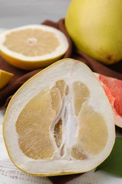 Different sorts of tasty pomelo fruits on white wooden table, closeup