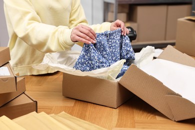 Post office worker packing parcel at wooden table indoors, closeup