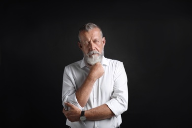 Portrait of handsome senior man on black background