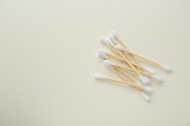 Heap of wooden cotton buds on beige background, flat lay. Space for text