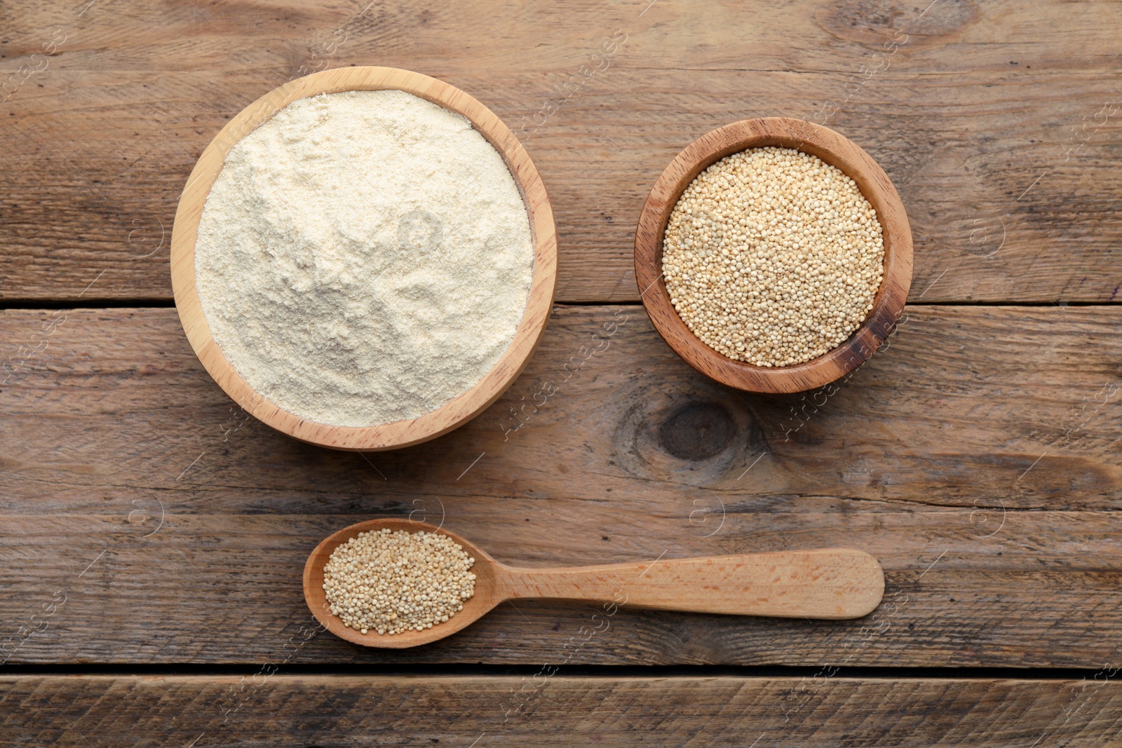 Photo of Quinoa flour in bowls and spoon with seeds on wooden table, flat lay