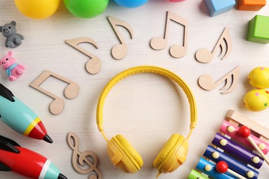 Baby song concept. Wooden notes, headphones and toys on table, flat lay