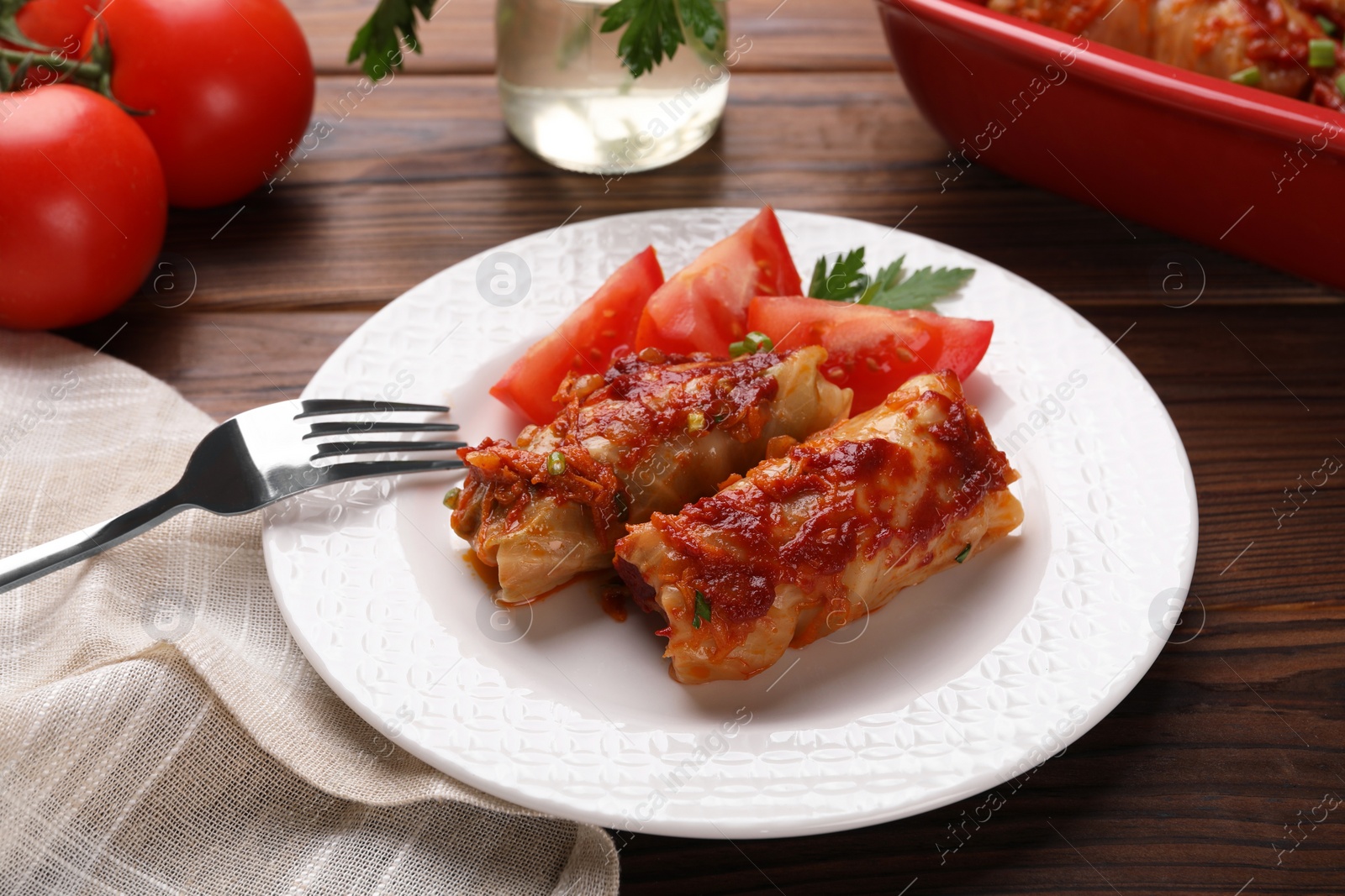 Photo of Delicious stuffed cabbage rolls with tomatoes served on wooden table, closeup