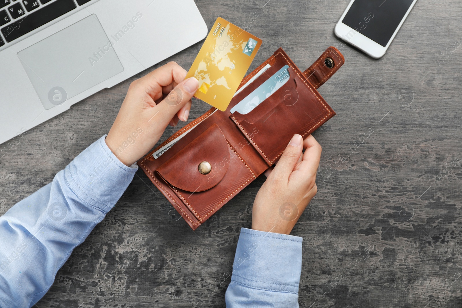 Photo of Woman holding leather wallet with credit cards on table, top view