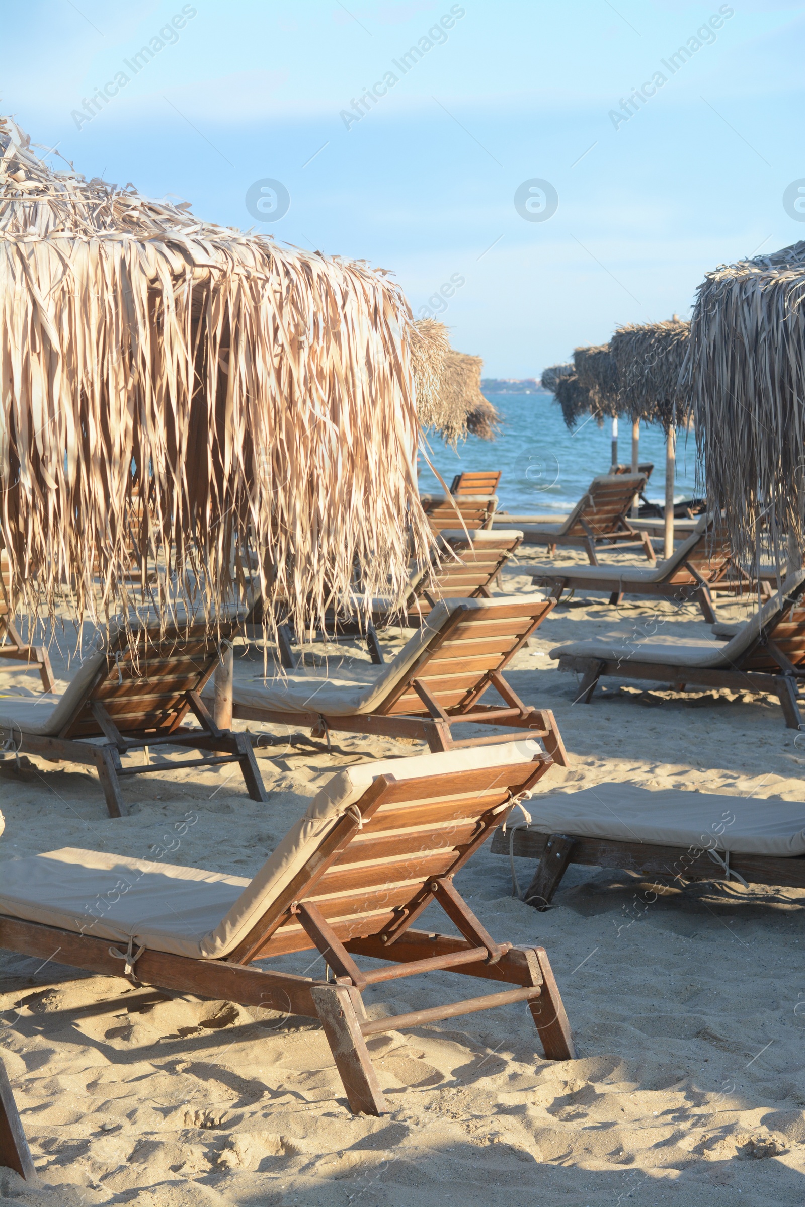 Photo of Beautiful straw umbrellas and wooden sunbeds on beach