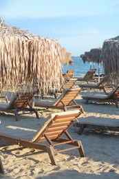 Beautiful straw umbrellas and wooden sunbeds on beach