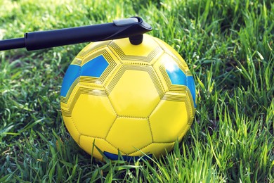 Photo of Inflating soccer ball with manual pump on green grass