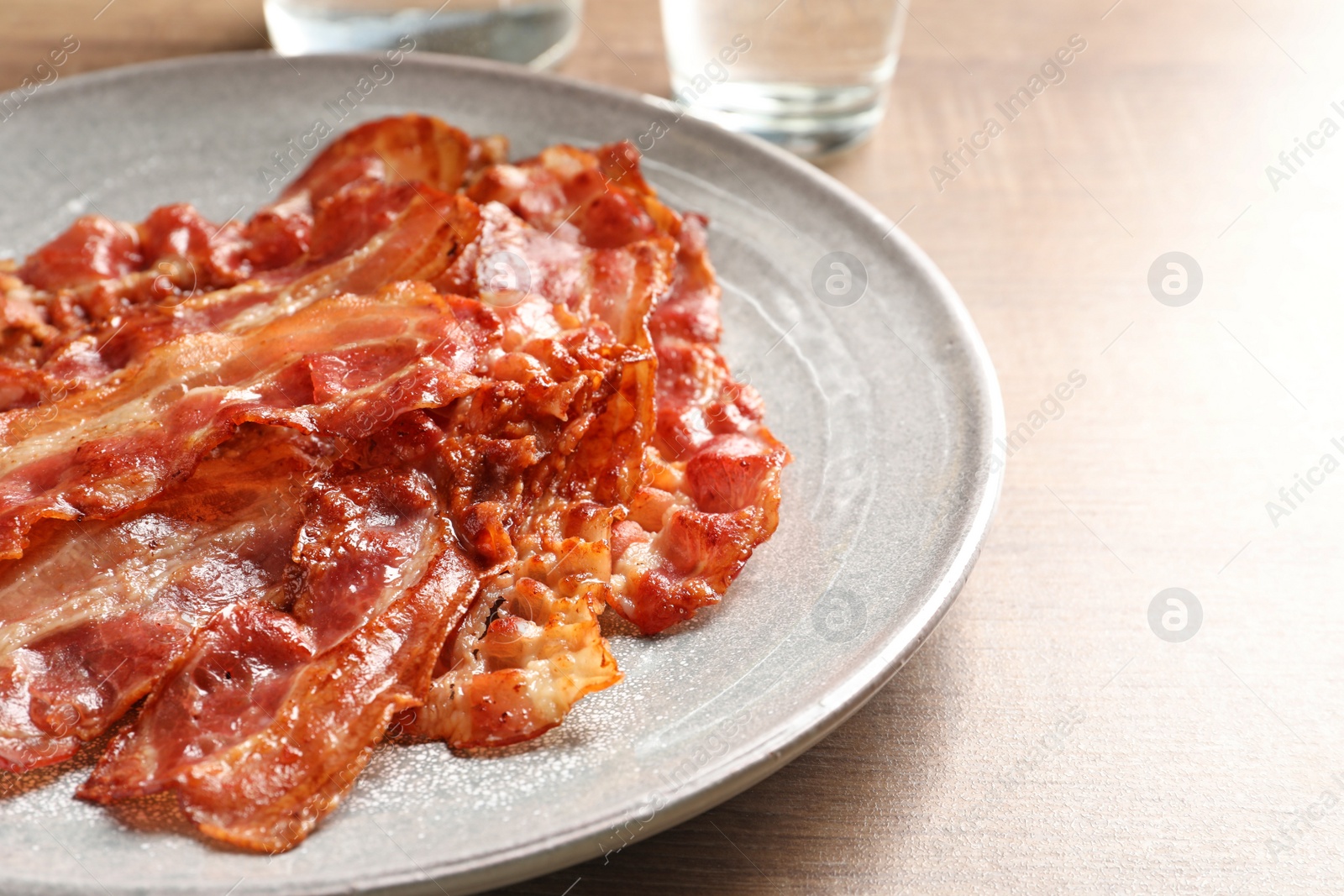 Photo of Plate with fried bacon on table