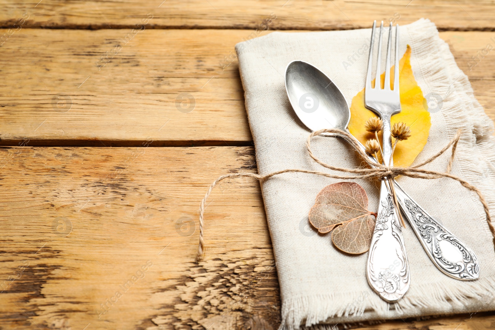 Photo of Seasonal table setting with autumn decor. Cutlery and fallen leaves on wooden background, space for text