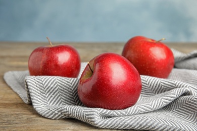 Photo of Ripe juicy red apples on wooden table against blue background