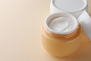 Photo of Jars of face cream on beige background, closeup. Space for text
