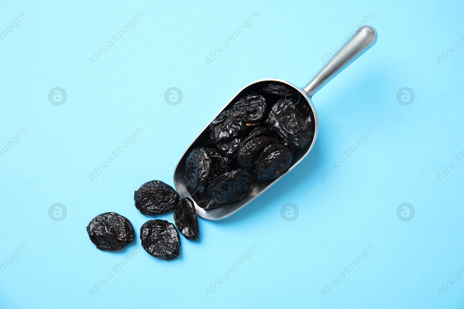 Photo of Scoop of dried plums on color background, top view. Healthy fruit