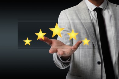 Image of Quality evaluation. Businessman showing virtual golden stars on black background, closeup