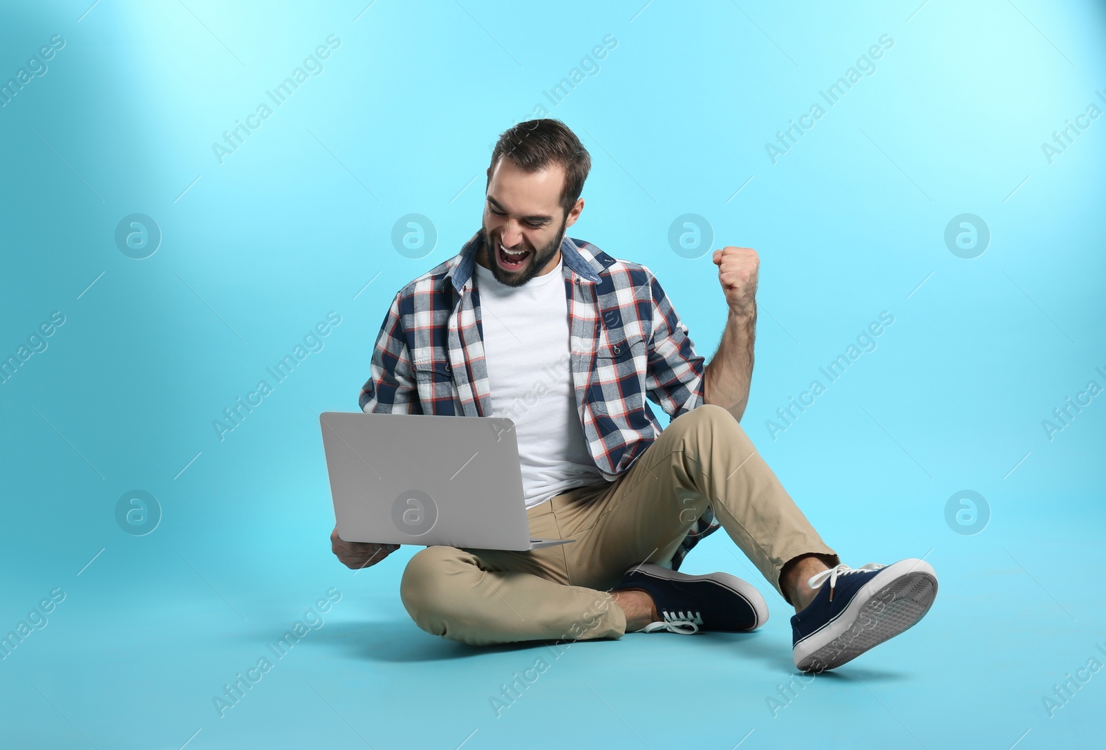 Photo of Emotional young man with laptop celebrating victory on color background