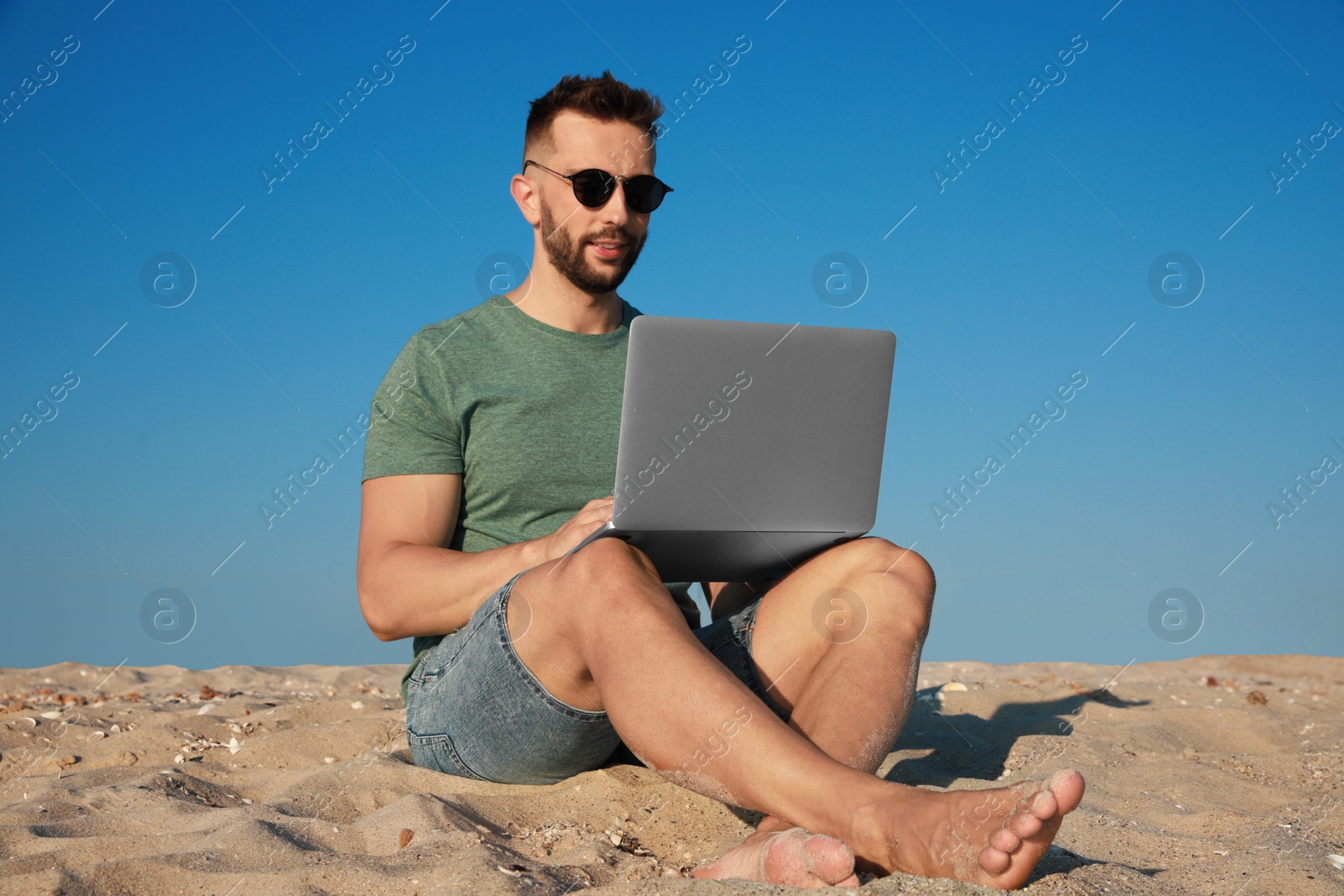 Photo of Man working with modern laptop on beach