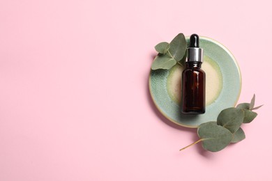 Aromatherapy product. Bottle of essential oil and eucalyptus leaves on pink background, top view. Space for text