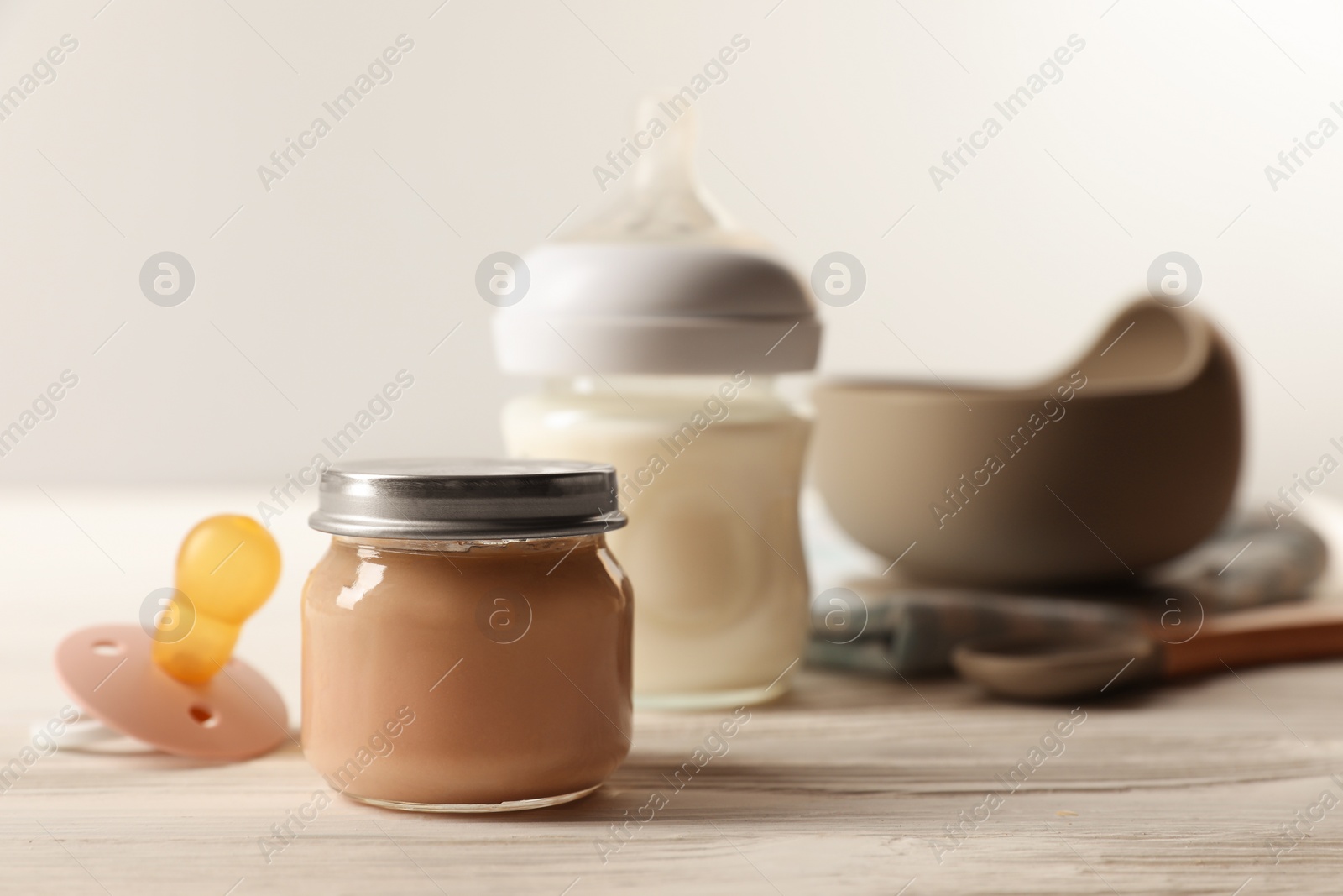 Photo of Jar with healthy baby food and pacifier on white wooden table. Space for text