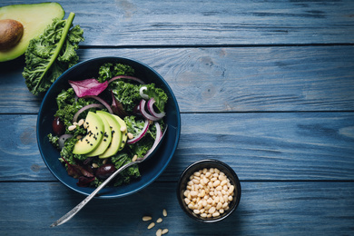 Image of Flat lay composition with tasty fresh kale salad on blue wooden table, space for text. Food photography  