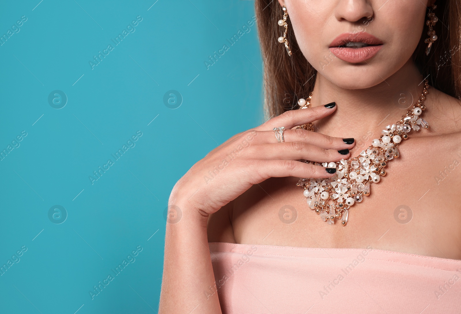 Photo of Beautiful woman with stylish jewelry on color background, closeup. Space for text