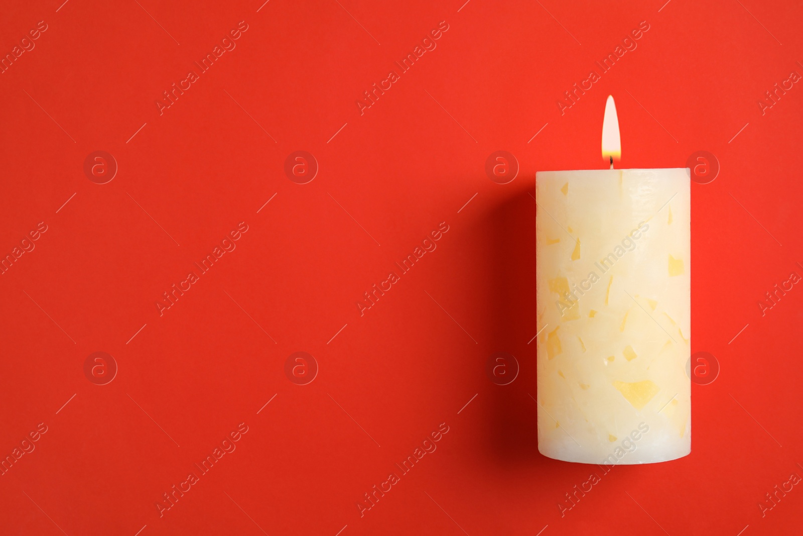 Photo of Alight wax candle and space for text on color background