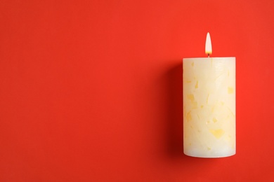 Photo of Alight wax candle and space for text on color background