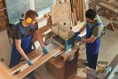 Photo of Professional carpenters working together in shop, view from above
