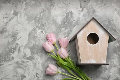Photo of Beautiful bird house and pink tulips on light grey background, flat lay. Spring composition with space for text