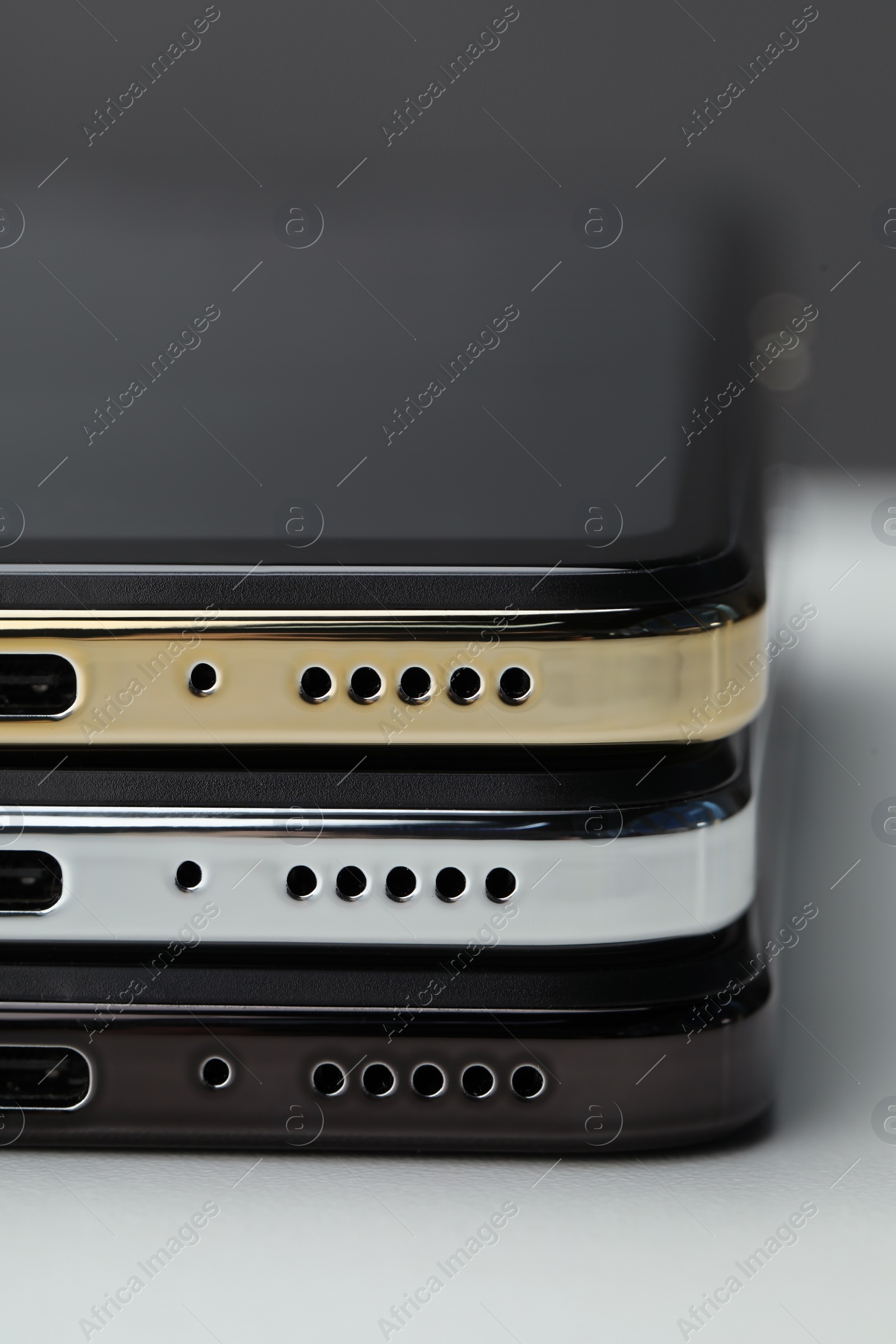 Photo of Stack of modern smartphones on white table, closeup