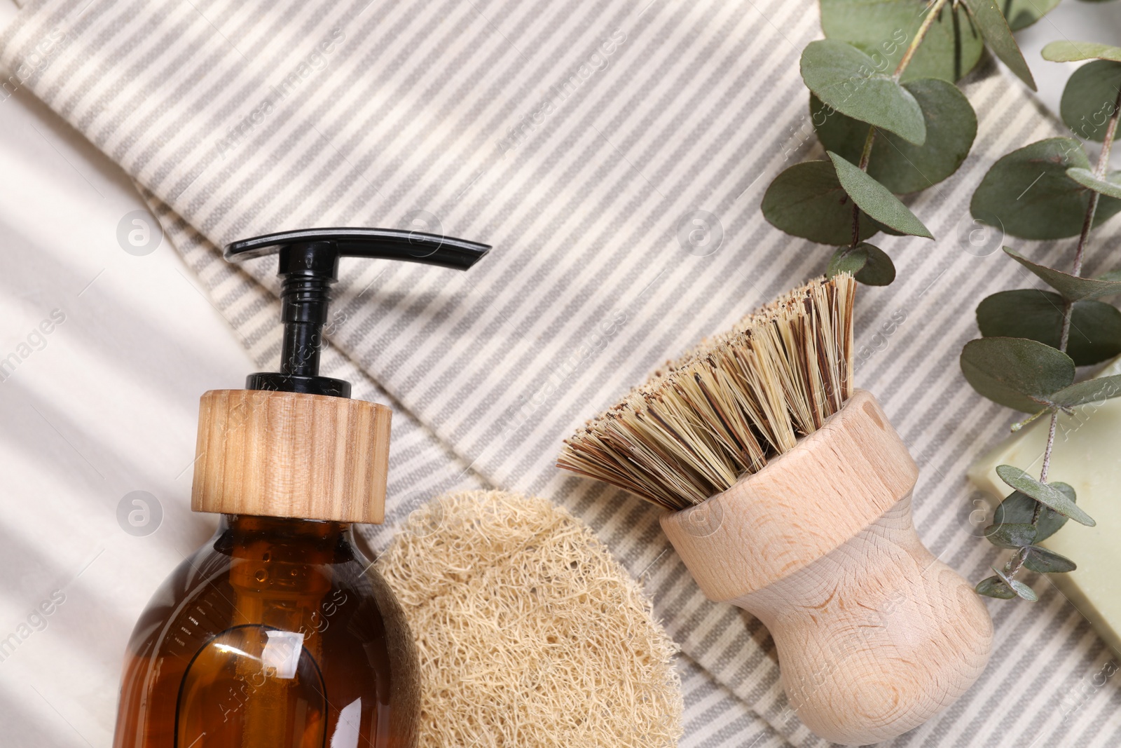 Photo of Cleaning brush, sponge, dispenser and eucalyptus leaves on table, top view