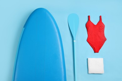 Flat lay composition with SUP board on light blue background. Water sport