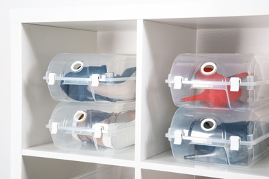 Photo of Footwear and plastic boxes on shelves near wall. Shoe storage organization