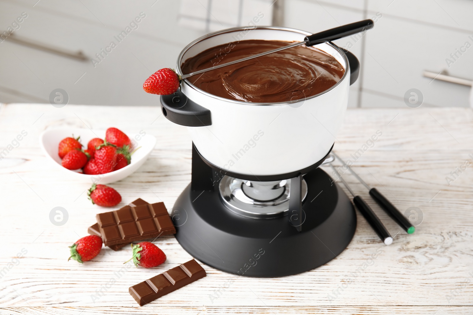 Photo of Chocolate fondue in pot and ripe strawberries on wooden table