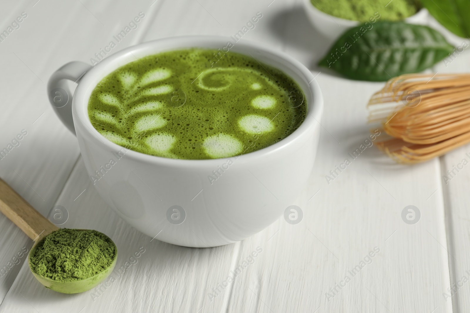 Photo of Delicious matcha latte and powder on white wooden table, closeup