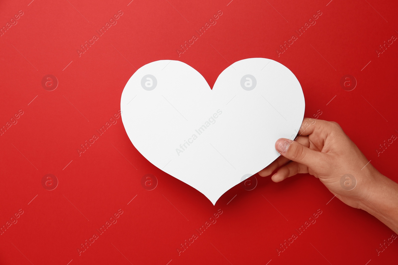 Photo of Woman holding blank paper heart on red background, closeup. Space for text