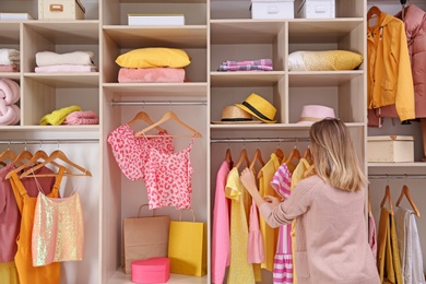 Woman choosing clothes from large wardrobe closet