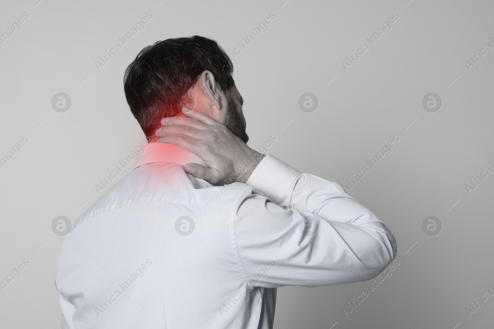 Image of Man suffering from neck pain on grey background, black and white effect