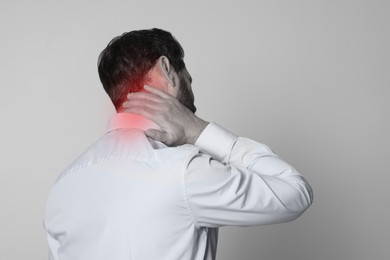 Man suffering from neck pain on grey background, black and white effect