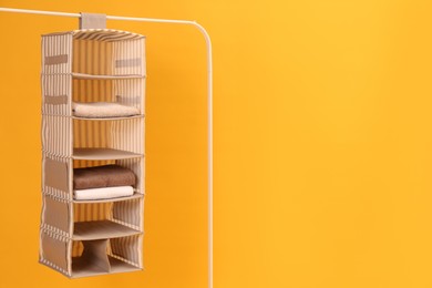 Photo of Foldable organizer on rack against yellow background. Space for text