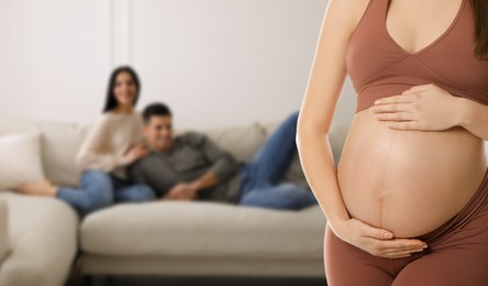 Surrogacy concept. Young pregnant woman and blurred view of happy couple indoors