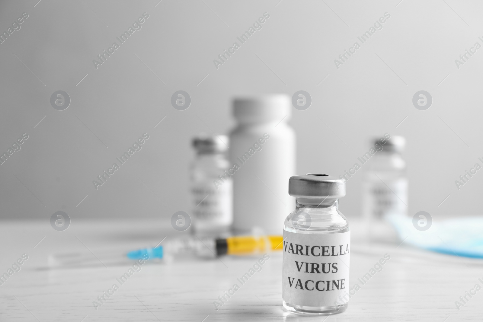 Photo of Chickenpox vaccine and syringe on white wooden table, space for text. Varicella virus prevention